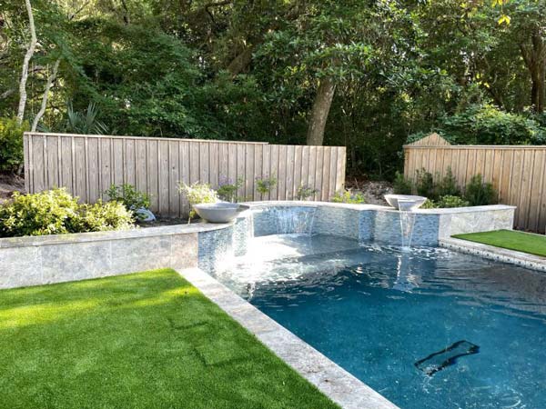 backyard with a pool surrounded by artificial grass in Jacksonville, FL