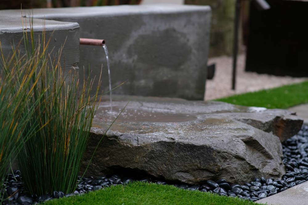 A serene water feature surrounded by grass and rocks in a Jacksonville, FL garden.